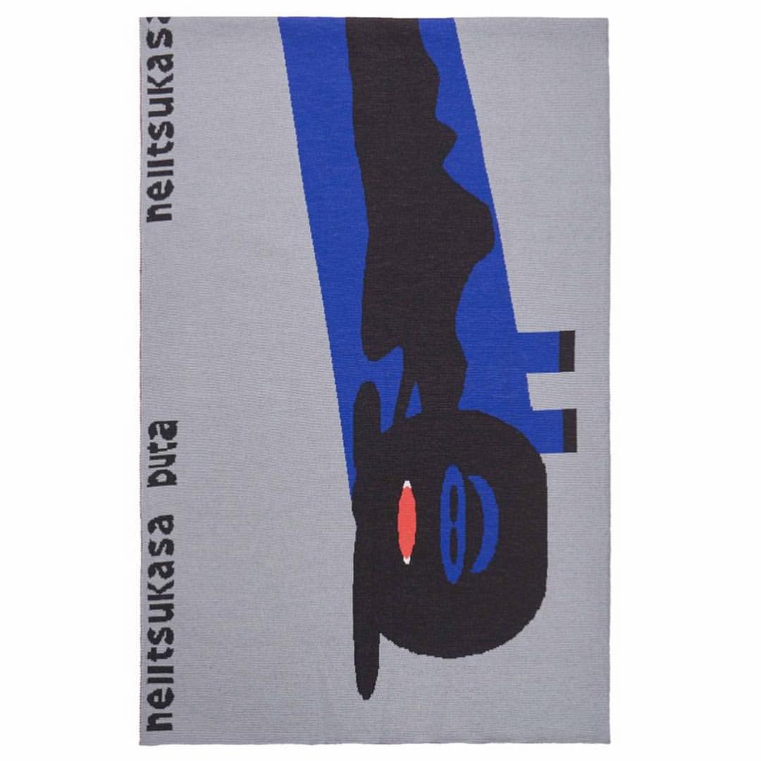 Graphic area rug features an abstract figure in black and blue with red accents on a grey background, adding a modern art element.