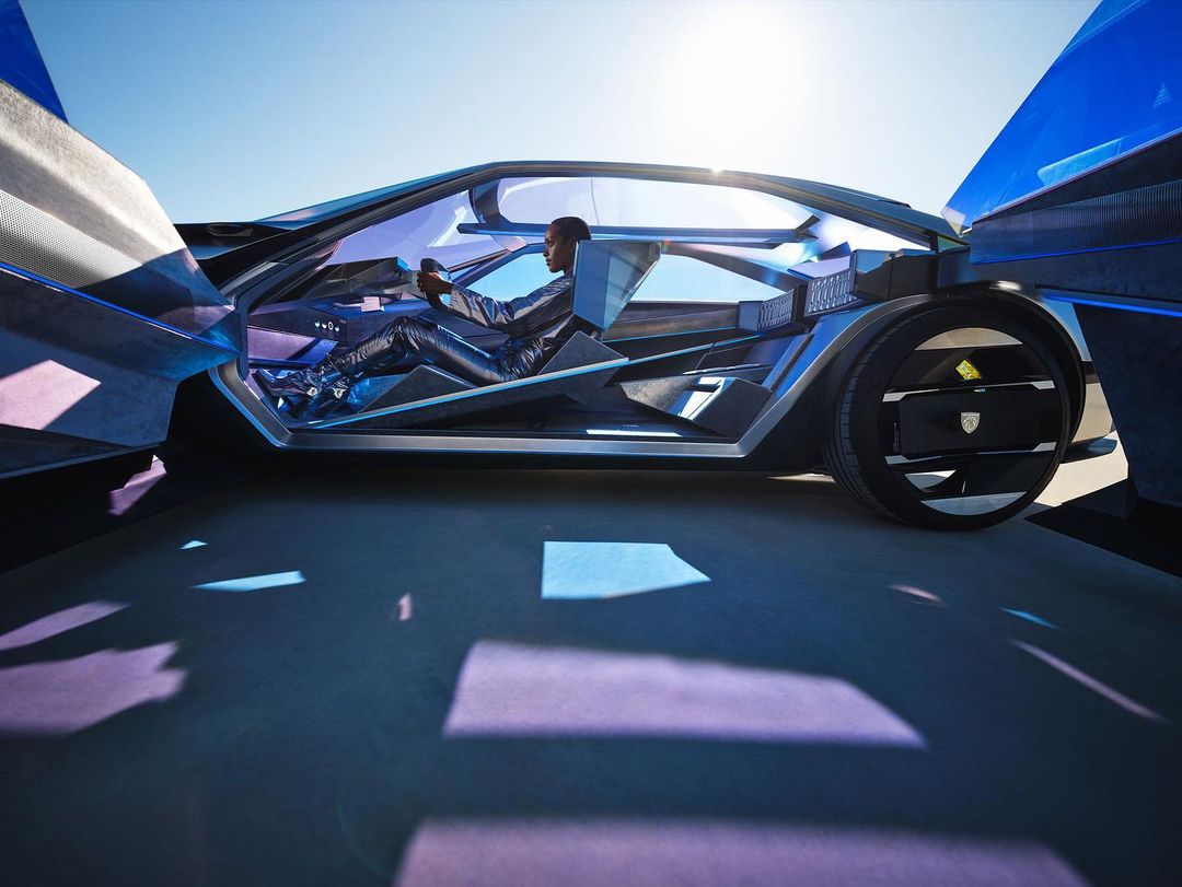 Futuristic concept car with open gull-wing doors on a sunny day, driven by an adult male in a black leather suit. Automotive design.