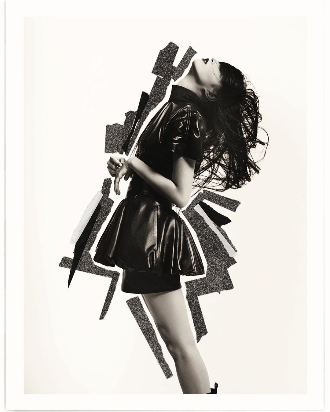 Stylish monochrome portrait of a woman in a black dress, with dynamic hair and artistic background. Fashion-forward and creatively composed.