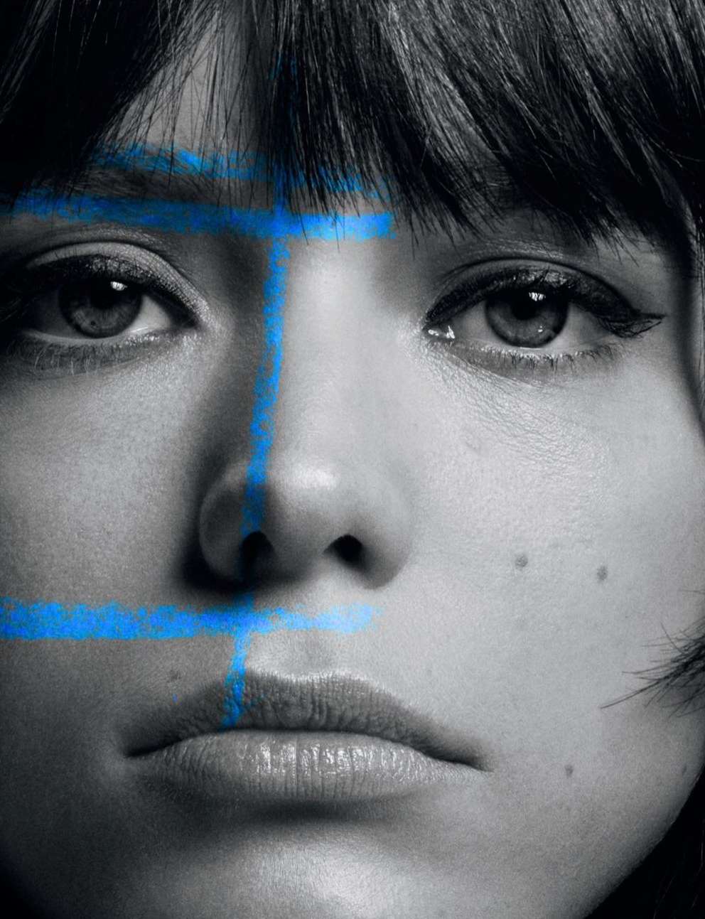 Portrait of a woman with blue painted lines on her face, creating a striking visual effect in a black and white photograph, close-up.