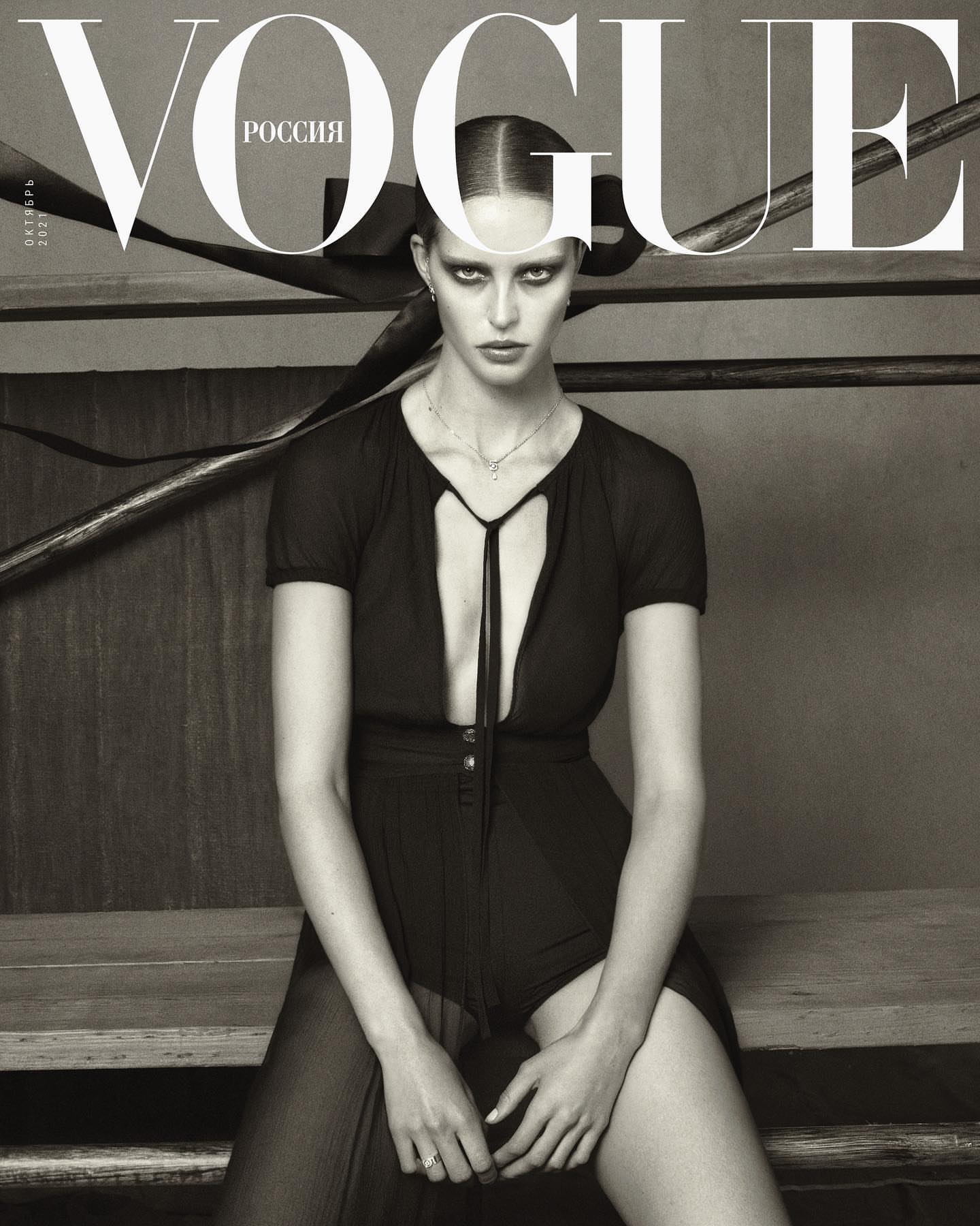 Black and white Vogue cover featuring a woman in a black outfit sitting on wooden steps with the masthead and text at the top.