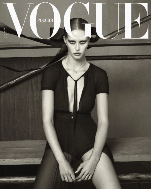 Black and white Vogue cover featuring a woman in a black outfit sitting on wooden steps with the masthead and text at the top.