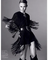 Model in black fringe top and leather boots standing against a neutral studio background