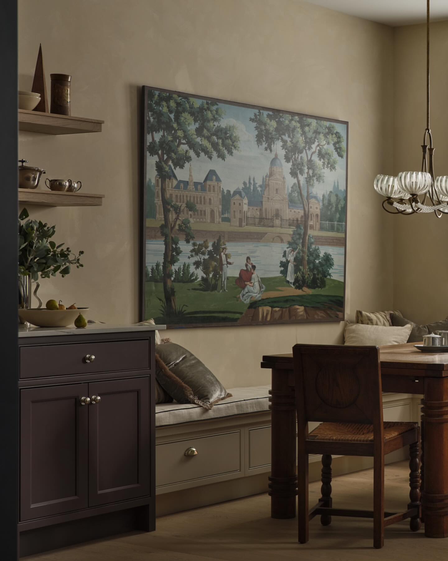 Dining area with brown table and chairs, a plum colored cabinet, and a large wall art featuring a historic landscape scene.