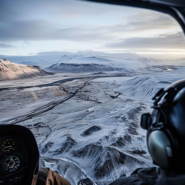 Aerial view from helicopter cockpit: A vast snow-covered landscape, mountains, and cloudy sky fill the scene, cockpit interior.