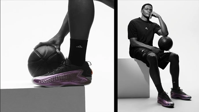 Promotional shot featuring a seated African-American male model wearing Adidas athletic wear and new iridescent shoes while holding a basketball.