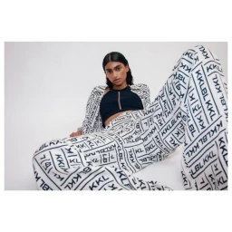 Model in printed patterned trousers and matching jacket with black crop top against a white seamless background