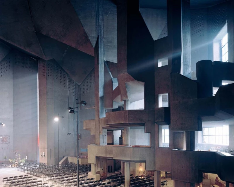 Interior view of the Saint Bernadette du Banlay church in France, featuring brutalist concrete architecture, rows of chairs and natural light.