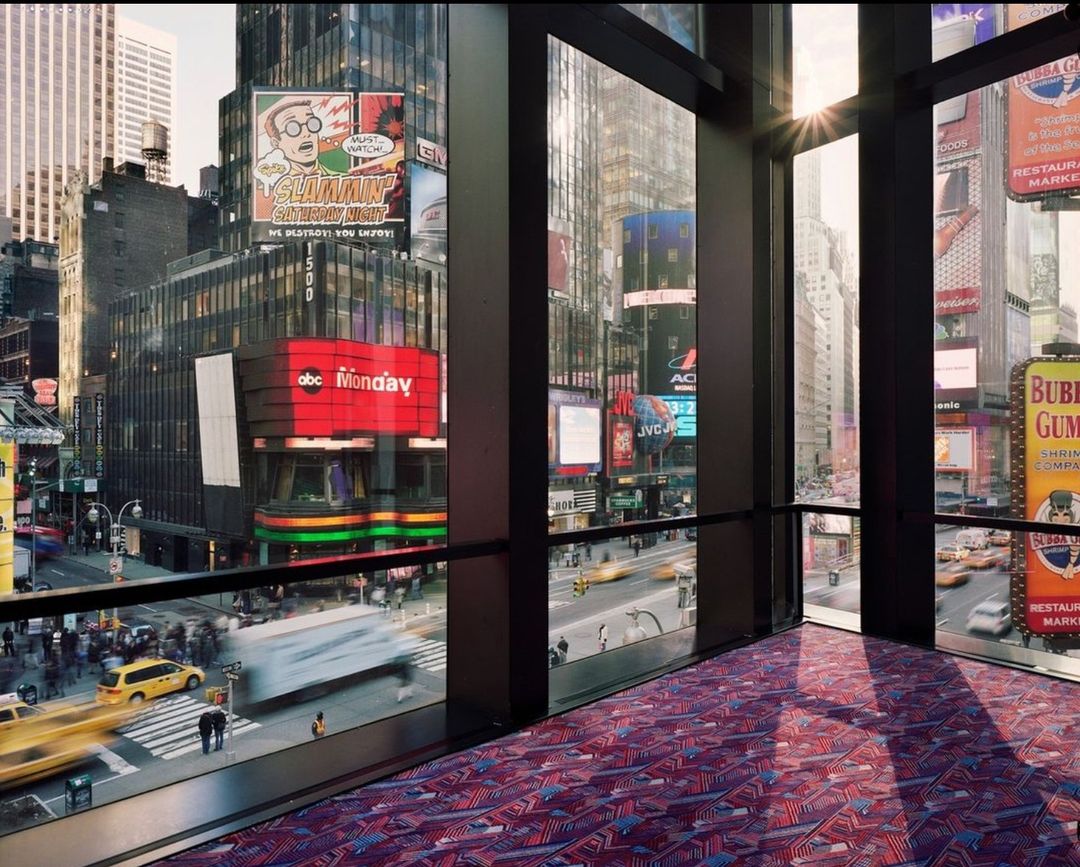 View from an indoor space overlooking a busy urban cityscape, featuring billboards, buildings, and pedestrian traffic.