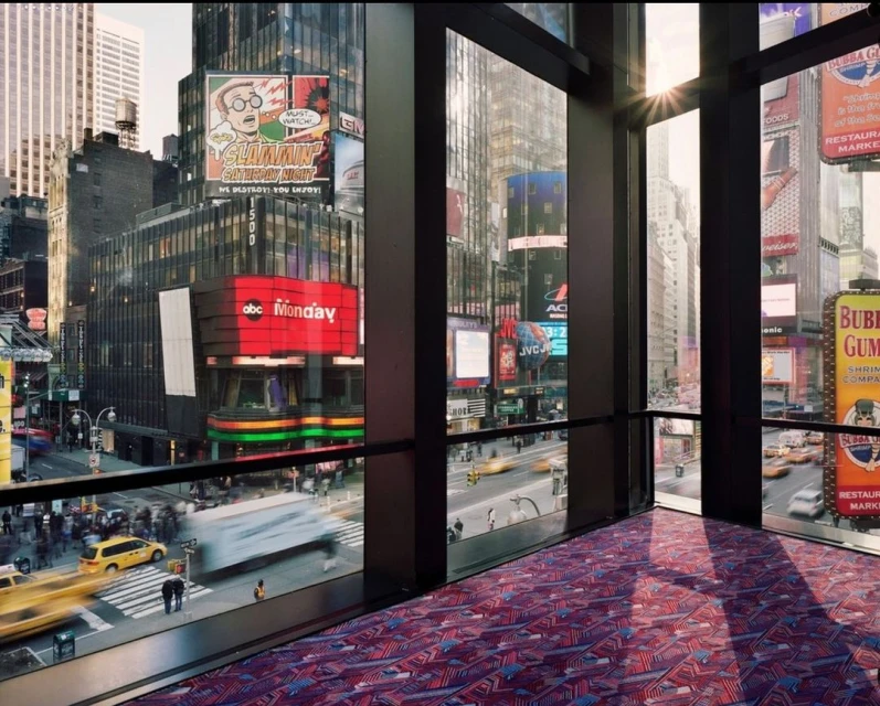 View from an indoor space overlooking a busy urban cityscape, featuring billboards, buildings, and pedestrian traffic.