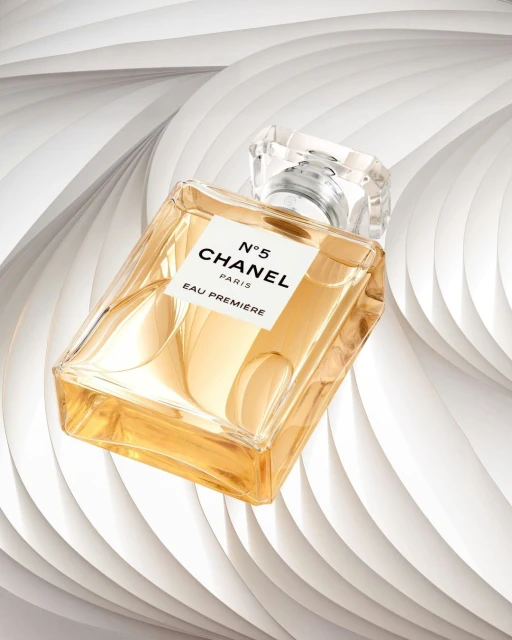 Angled view of a Chanel N°5 Eau Premiere perfume bottle against a white abstract background, showcasing luxury and elegant fragrance.
