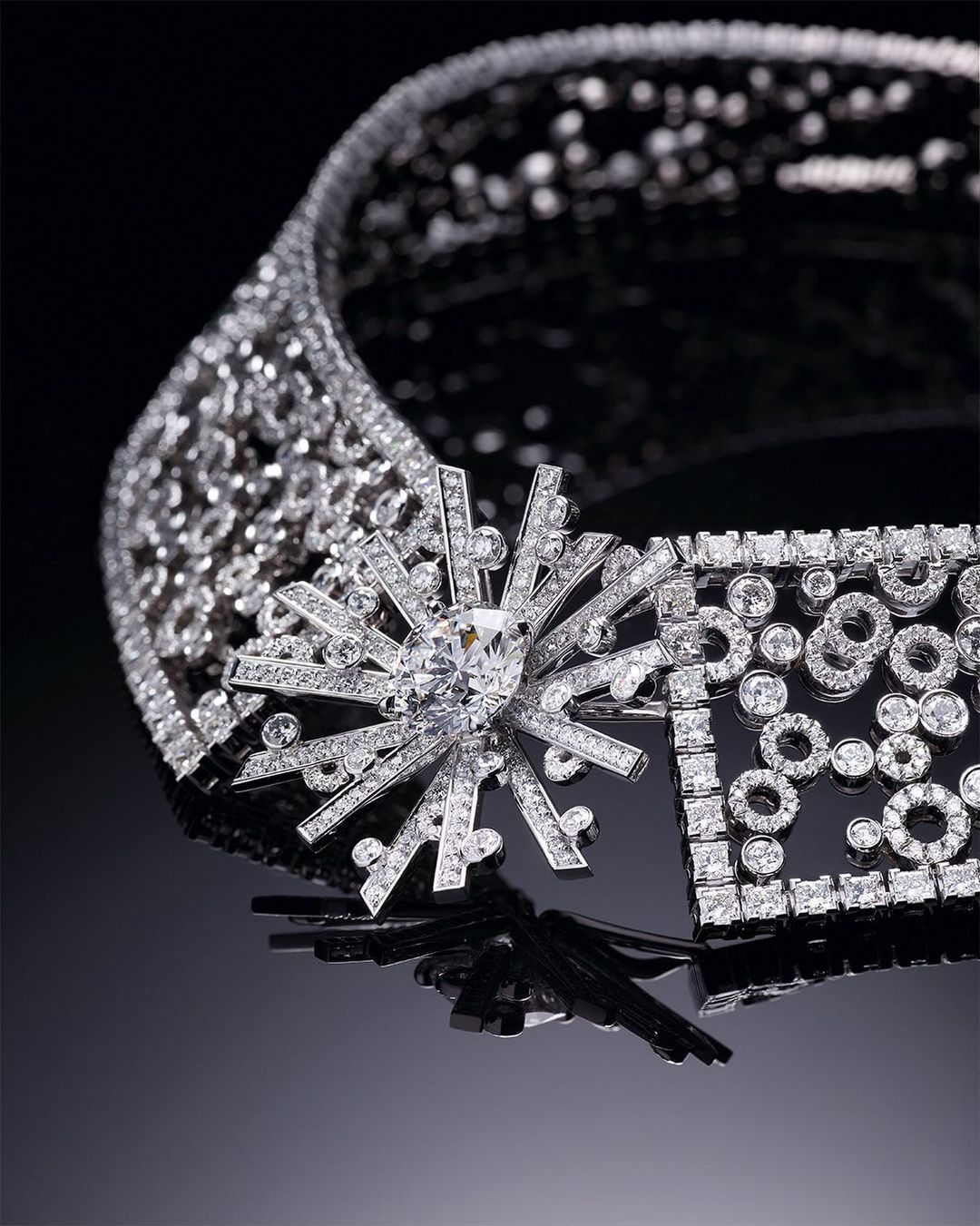 Elegant diamond necklace on a glossy black surface, featuring intricate lattice work and a starburst pendant; luxury jewellery photography.