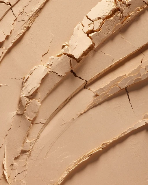 Close-up of beige powder with cracked, textured surface, showcasing its fine texture and subtle color variations.