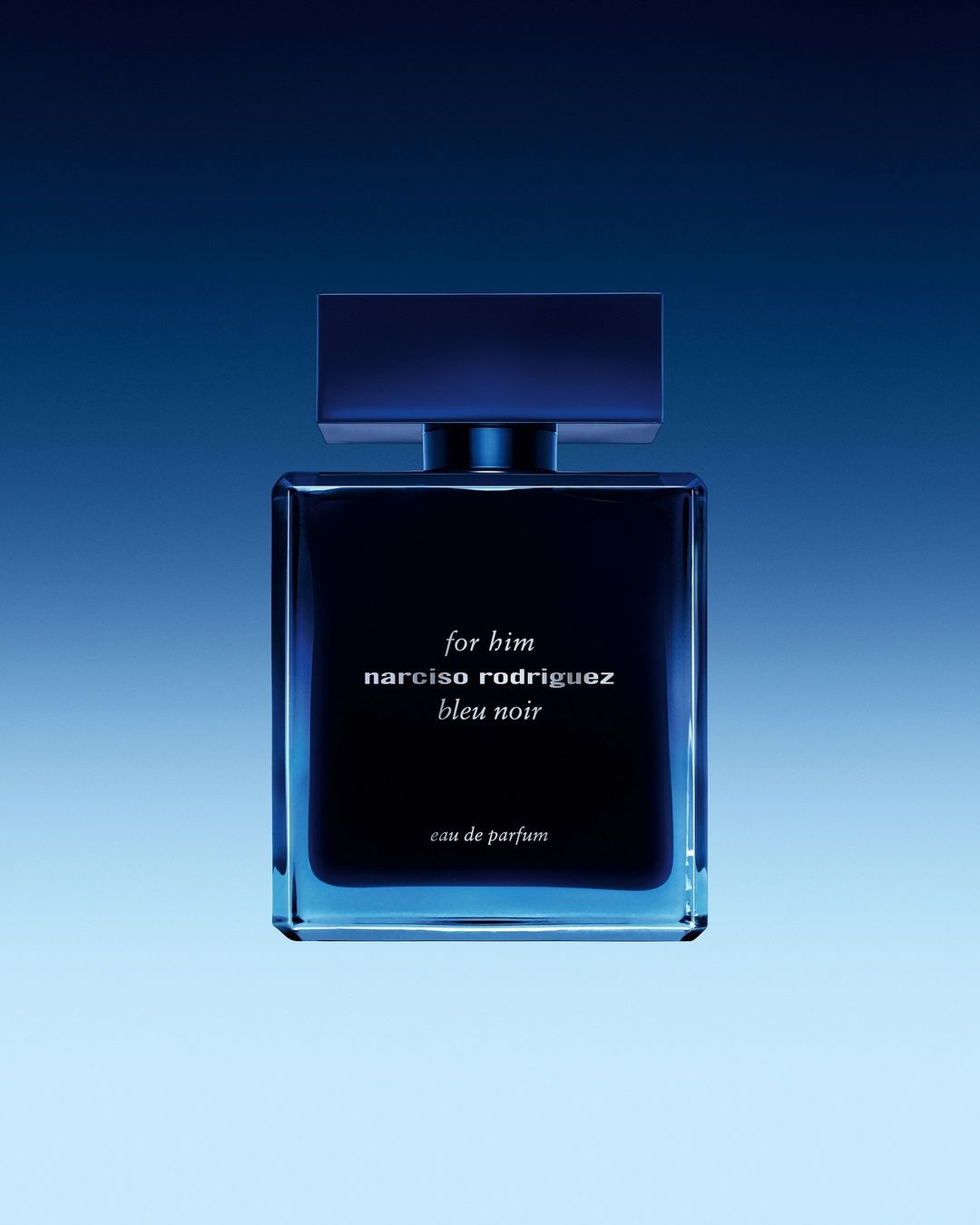 Square, blue bottle of Narciso Rodriguez Bleu Noir eau de parfum against a gradient blue background in a studio product shot.