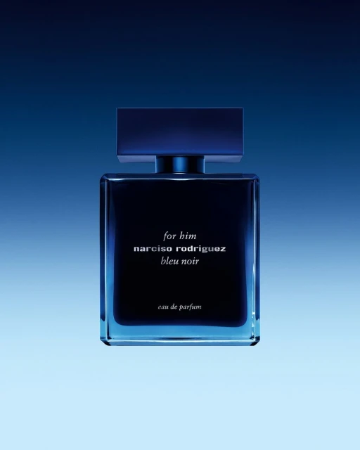 Square, blue bottle of Narciso Rodriguez Bleu Noir eau de parfum against a gradient blue background in a studio product shot.