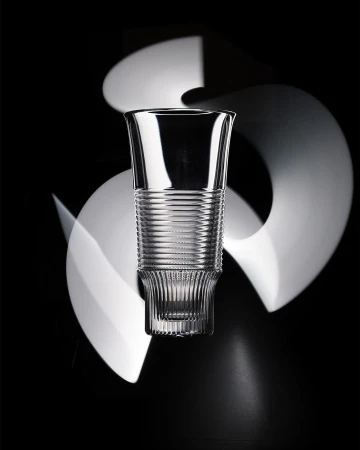 Elegant crystal glass with ribbed details on a dark backdrop with blurred white light streaks creating a dynamic, eye-catching visual effect.