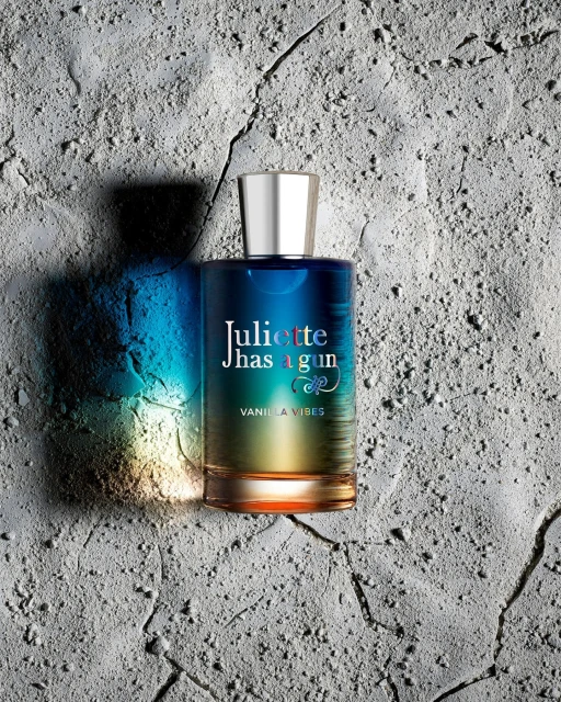 Juliette Has A Gun Vanilla Vibes perfume bottle on textured grey background with blue and yellow gradients on the bottle.