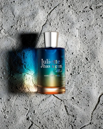 Juliette Has A Gun Vanilla Vibes perfume bottle on textured grey background with blue and yellow gradients on the bottle.