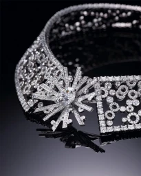 Close-up of an intricate diamond necklace with geometric and starburst motifs resting on a dark reflective surface.