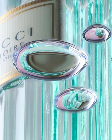 Close-up of a glass Gucci perfume bottle with water droplets and reflective surfaces creating a visually interesting and elegant composition.