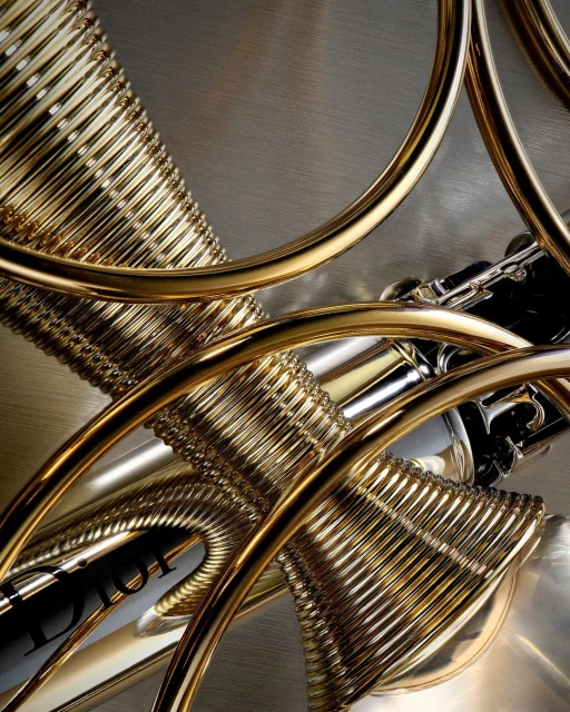 Abstract fashion still life features gold and silver perfume bottles with concentric circles against a textured metal background.