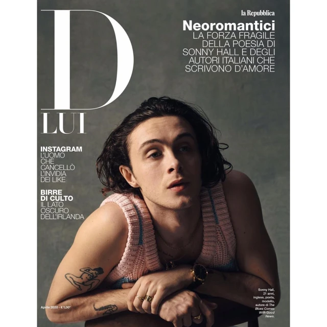 Magazine cover featuring a young adult male with dark hair wearing a knit tank top and gold rings and watch posing indoors.