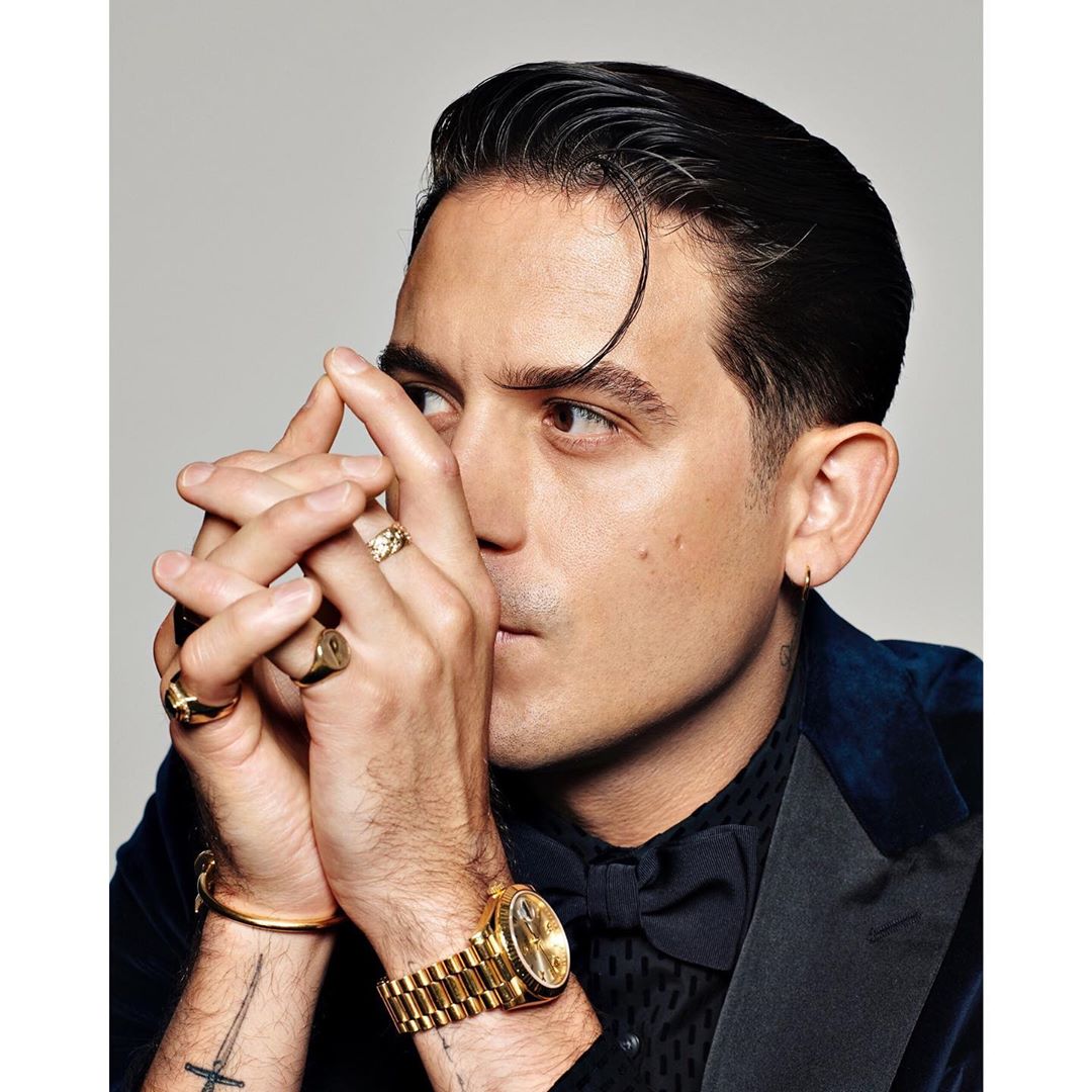 Portrait of G-Eazy, also known as Gerald Earl Gillum, wearing gold jewelry, a black bow tie, and a blue velvet tuxedo jacket.