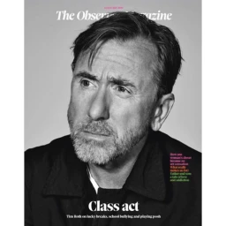 Portrait of actor Tim Roth with a trimmed gray beard wearing a dark jacket against a seamless gray studio background.