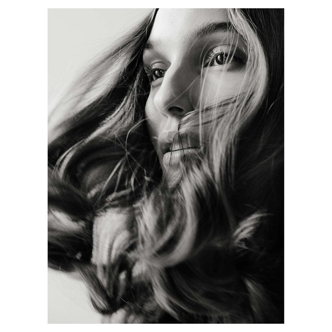 Close up monochrome portrait of a woman with long dark hair blowing across her face in London by photographer Christopher Anderson.