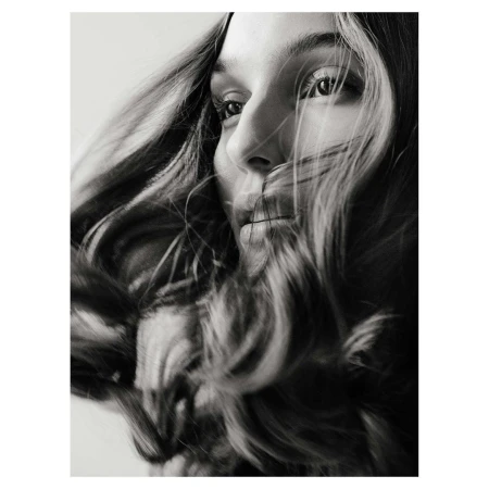 Close up monochrome portrait of a woman with long dark hair blowing across her face in London by photographer Christopher Anderson.