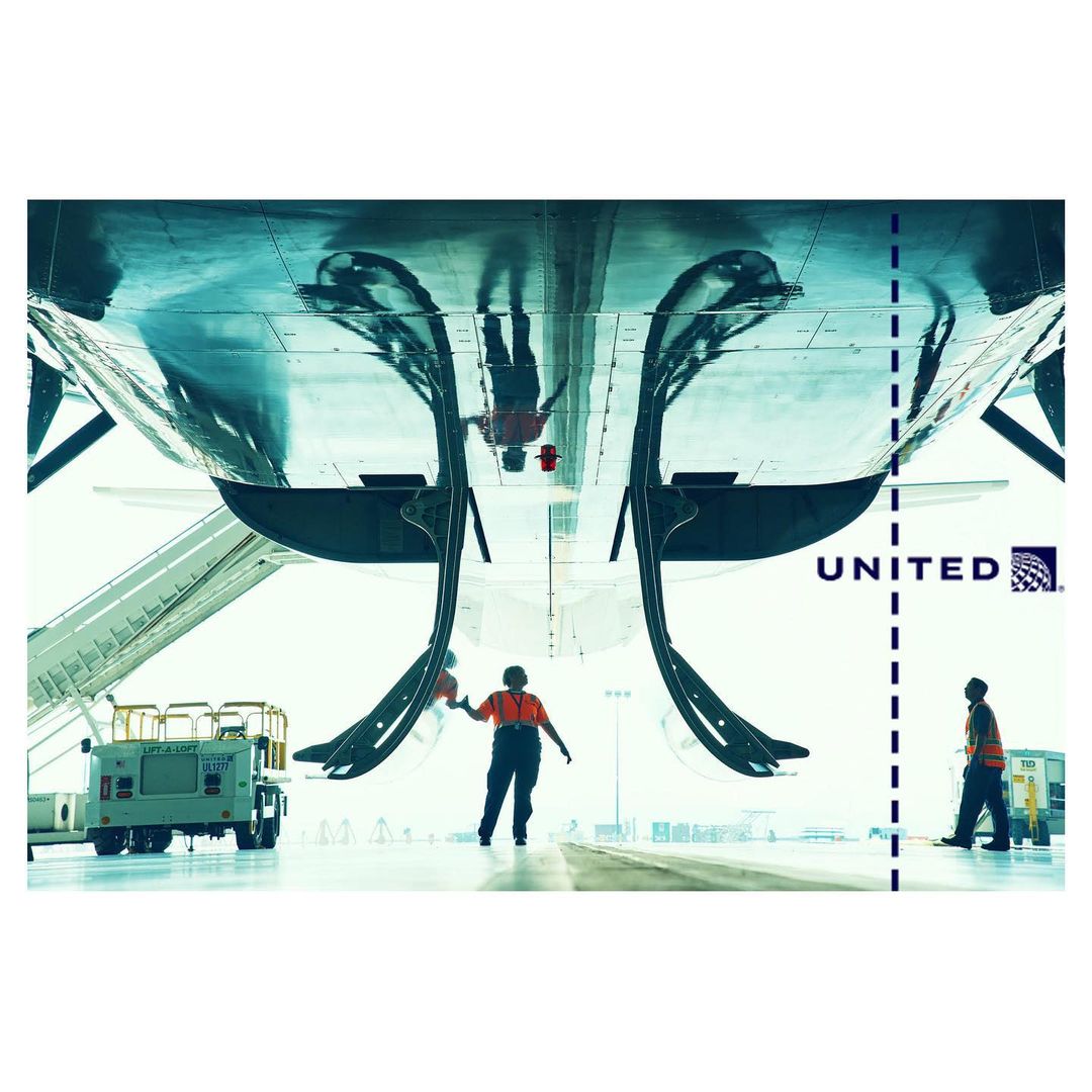 Airplane maintenance scene with two workers standing near the aircraft, with ground equipment and the United Airlines logo visible.