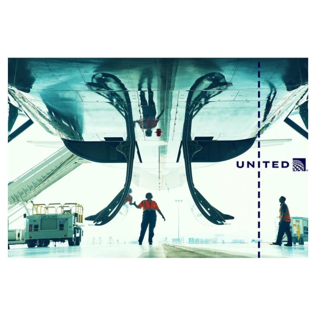 Airplane maintenance scene with two workers standing near the aircraft, with ground equipment and the United Airlines logo visible.