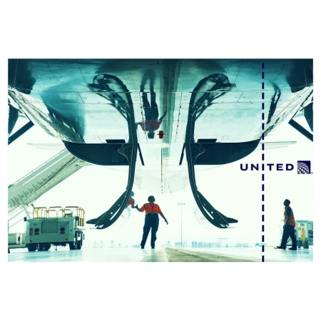 Airplane maintenance scene with two workers standing near the aircraft, with ground equipment and the United Airlines logo visible.