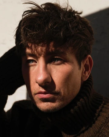Close-up portrait of actor Barry Keoghan wearing a dark ribbed turtleneck sweater in bright sunlight with harsh shadows.