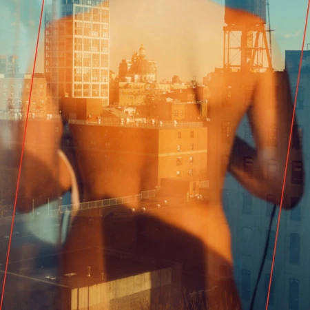 Abstract double exposure of a partially undressed person in a city, featuring building silhouettes and an orange-and-blue color palette.