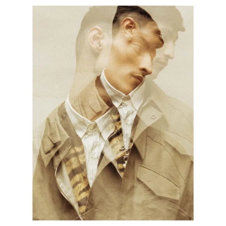 Fashionable man with multiple exposures wearing a beige jacket and striped shirt, posing in a photo studio with warm-toned lighting.