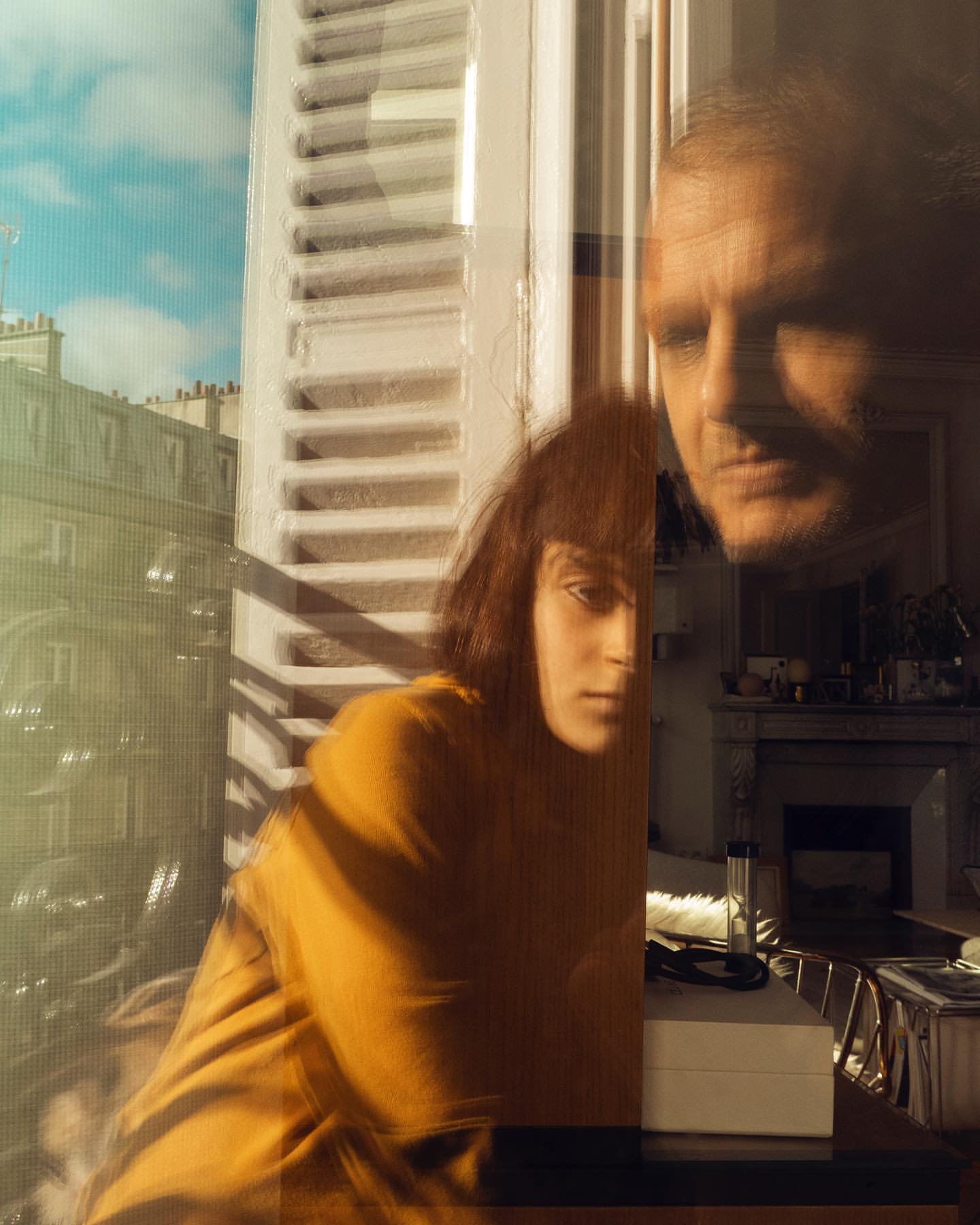 Indoor portrait featuring a young adult with a bob haircut and a mature adult, captured in a soft, window-lit setting within an apartment.