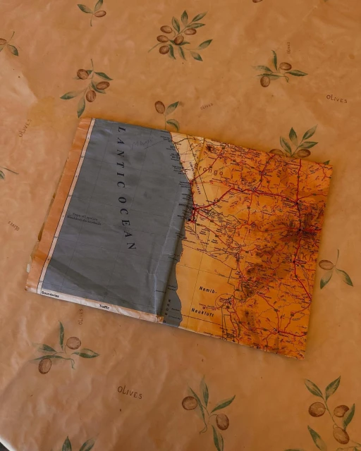 Open world map on an olive-patterned tablecloth, displaying orange landmasses and a blue ocean labeled 'Atlantic Ocean'.