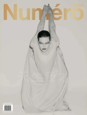 Fashion magazine cover featuring a model in a light-colored gown with hands raised, against a white background with gold lettering.