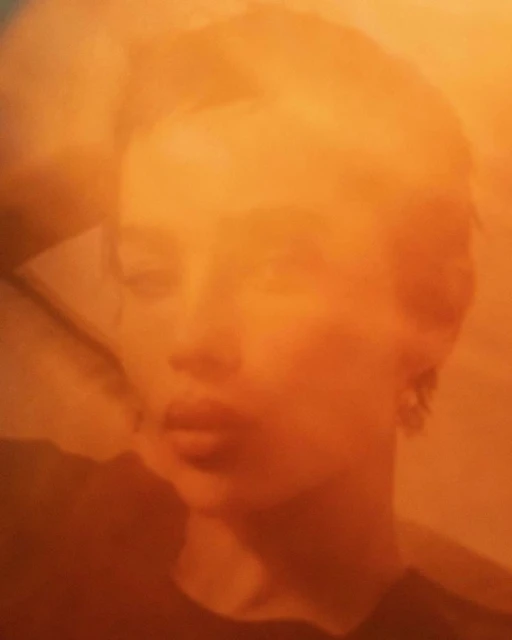 Portrait of a woman with short hair in warm tones, featuring soft focus and shallow depth of field in an indoor setting.