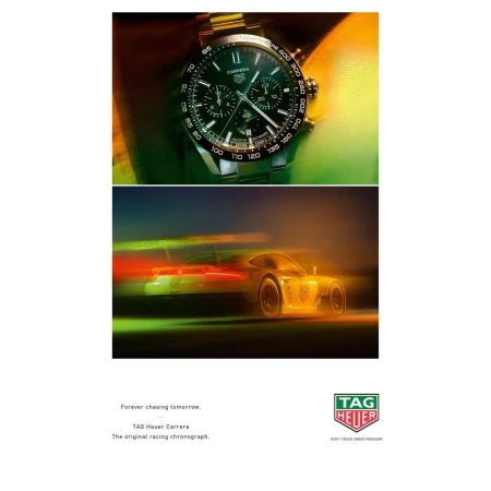 Gold TAG Heuer Carrera watch on a wrist above a blurred race car in motion, showcasing a blend of luxury and automotive speed.