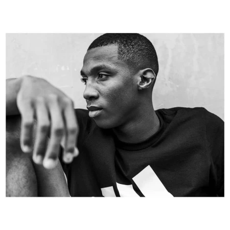 Close-up monochrome portrait of a young Black man wearing a graphic t-shirt, shot by photographer Christopher Anderson.