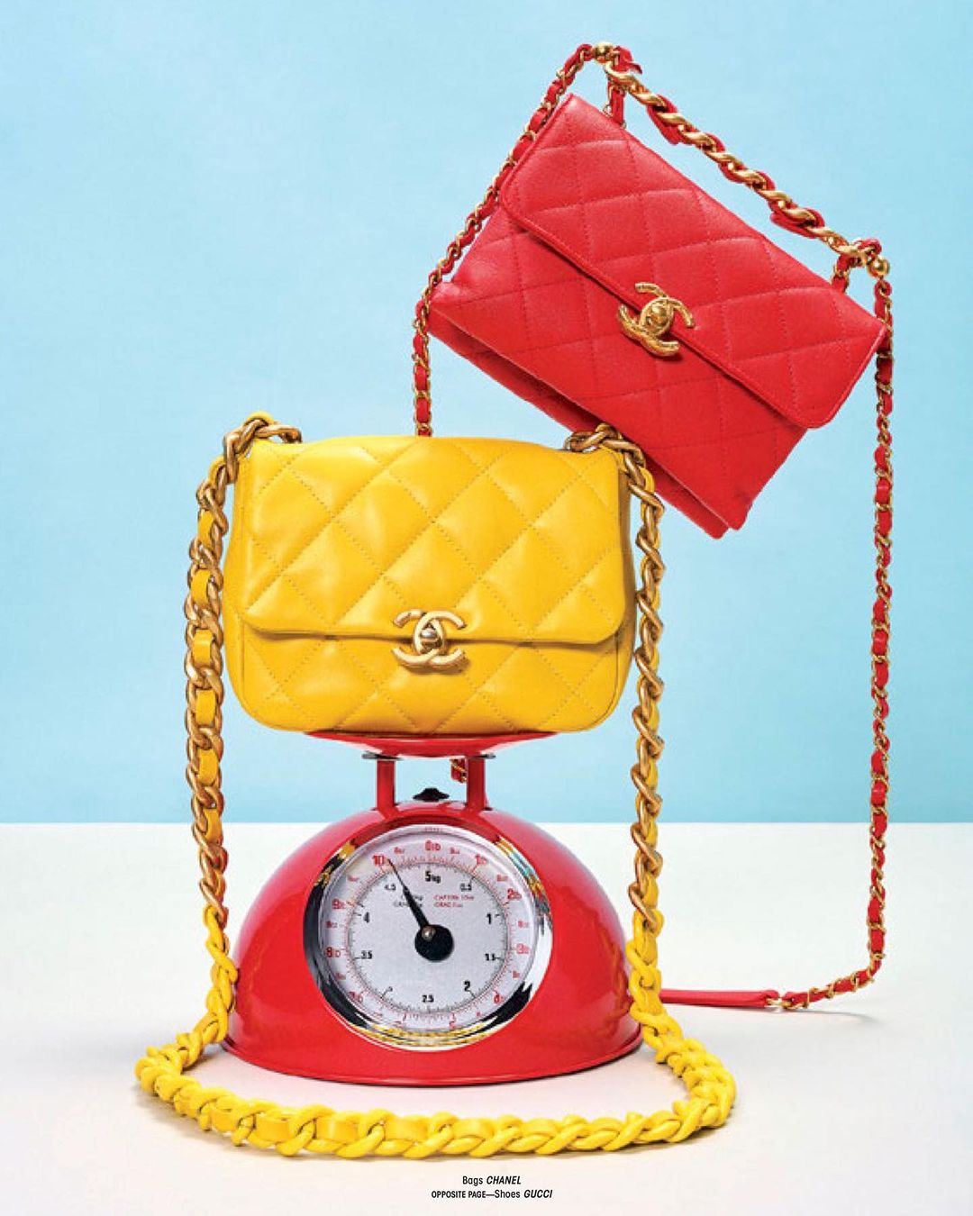 Still life fashion product shot of a yellow quilted chain bag on a red kitchen scale with a red quilted chain bag floating behind.