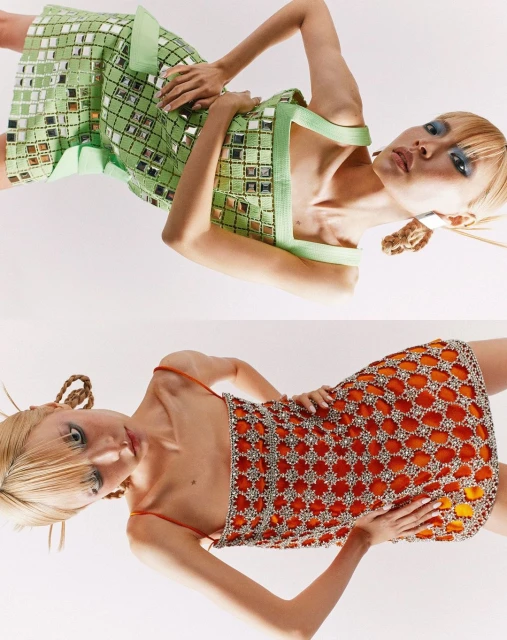 Two women pose in mirrored dresses against a white background, showcasing avant-garde fashion with unique textural and reflective qualities.