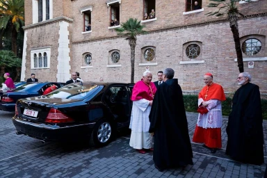 Pope Benedict XVI stepping out of a black Mercedes Benz near a brick building, photographed by Christopher Pillitz