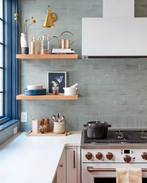 Modern kitchen with subway tile backsplash, open wood shelving, and black pot on the white and stainless steel range.