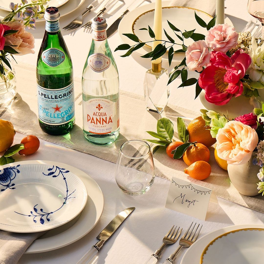 Elegant table setting with water bottles, flower arrangements, and place settings featuring fine china and silverware.