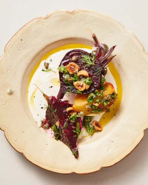 Overhead shot of beet salad on a decorative plate with herbs, nuts, and a creamy sauce creating a vibrant, appetizing presentation.