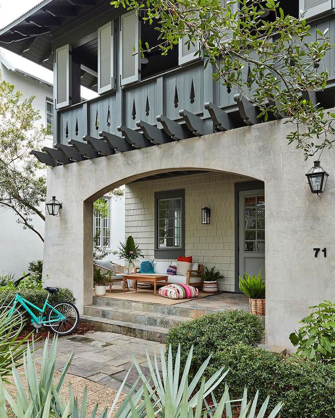 Outdoor living space with a turquoise bicycle, stone steps, a seating area, and lush plants creating a cozy and inviting atmosphere.