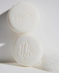 Two white embossed soaps stacked vertically with soap suds against a bright white background